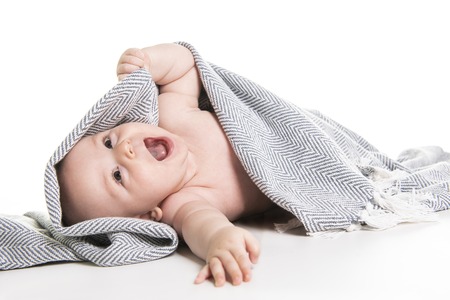 baby under a towel isolated on a white backgroundの写真素材