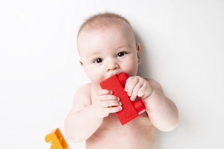 Baby boy plays with toy blocks over white backgroundの写真素材