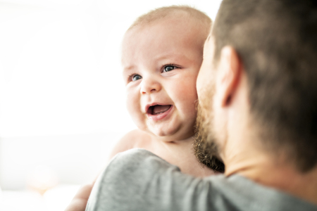 family father with baby boy in front of windowの写真素材
