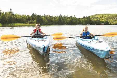 Summer vacation Portrait of cute boy and girl kayaking the on riverの写真素材