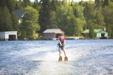 Child learning to water skiing on a lakeの写真素材