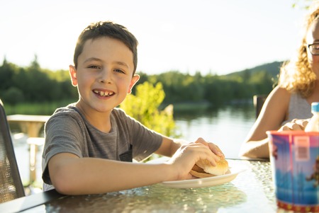 boy eating hamburger outside with his familyの写真素材