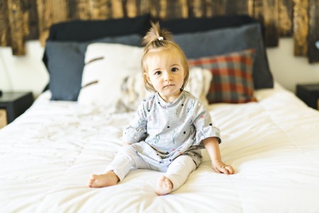 Cute little baby girl on bed at home