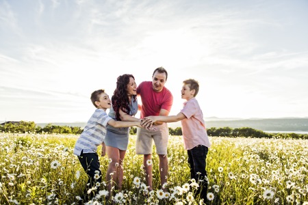 Happy family having fun on daisy field at sunsetの写真素材