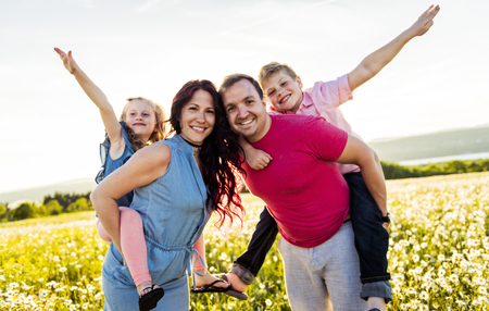 Happy family having fun on daisy field at sunset