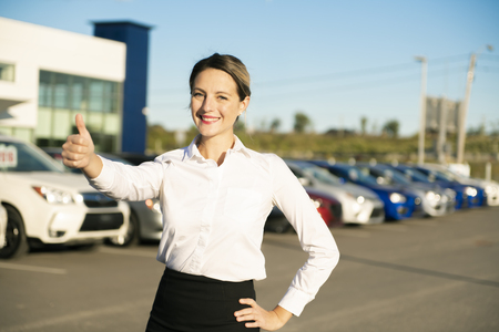 Young woman car rental in front of garage with cars on the backgroundの写真素材