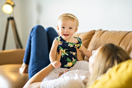happy family. Mother and baby daughter plays, on the sofaの写真素材