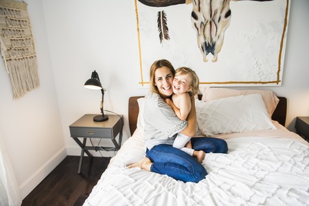 Young mother with her little son relaxing and playing in the bed at the weekend togetherの写真素材