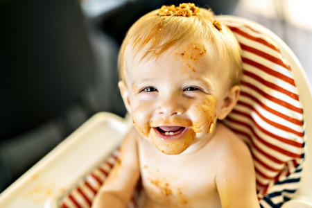 Little baby eating spaghetti dinner and making a mess