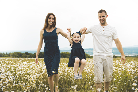 parent walking with her baby son on daisy field at the sunset timeの写真素材