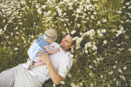 little baby girl and his father enjoying outdoors in field of daisy flowersの写真素材