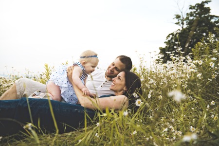 littlegirl and his father and mother enjoying outdoors in field of daisy flowersの写真素材