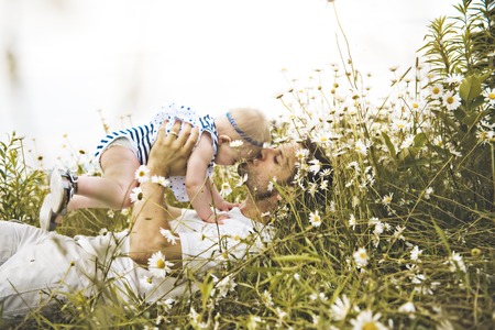 little baby girl and his father enjoying outdoors in field of daisy flowersの写真素材