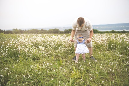 little baby girl and his father enjoying outdoors in field of daisy flowersの写真素材