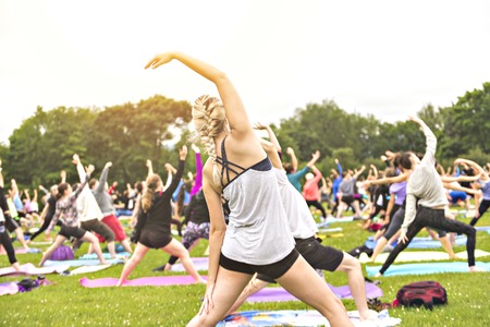 big group of adults attending a yoga class outside in parkの写真素材