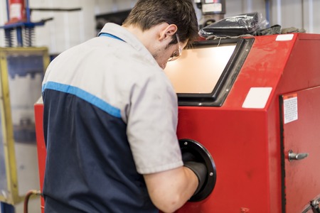 Handsome mechanic job in uniform working on car part