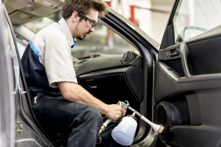 Man at work cleaning inside automobile at car washの写真素材