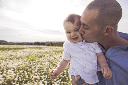 little boy and his father enjoying outdoors in field of daisy flowersの写真素材