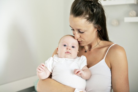 Portrait of a beautiful mother with her 2 month old baby in the bedroom