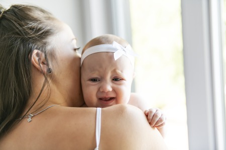 Portrait of a beautiful mother with her 2 month old baby in the bedroom