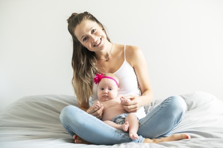 Portrait of a beautiful mother with her 2 month old baby in the bedroomの写真素材