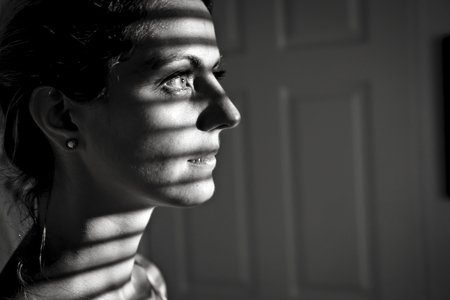 Depressed young woman near window at home, closeup