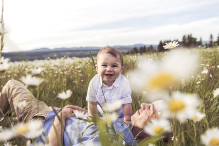 little boy and his father enjoying outdoors in field of daisy flowers