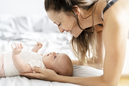 Portrait of a beautiful mother with her 2 month old baby in the bedroomの写真素材