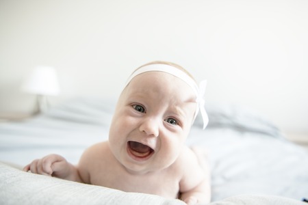 Adorable two months baby girl relaxing in bedroom on knitted blanket on a sunny morningの写真素材