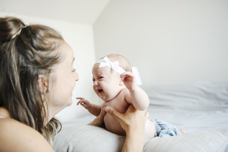 Portrait of a beautiful mother with her 2 month old baby in the bedroomの写真素材