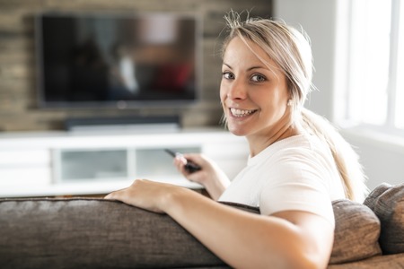 Young woman watching TV in the living roomの写真素材