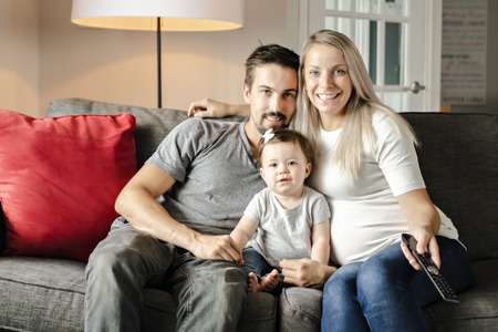 Family mother, father, child daughter at home listening tvの写真素材