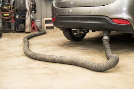 Car undergoing repair or a service in a workshop with focus to the exhaust pipeの写真素材