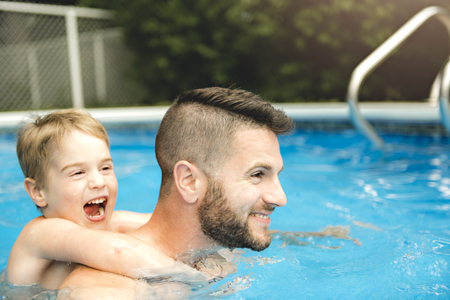 Cute little boy learning to swim with parents in poolの写真素材