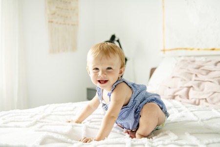 Cute baby girl on bed at homeの写真素材