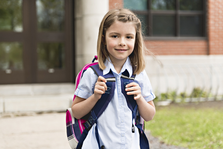 Portrait of cute girl with backpack outside of schoolの写真素材