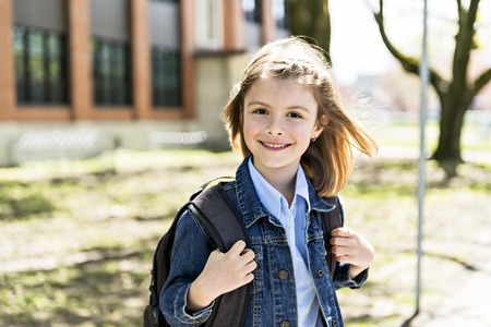Portrait of cute girl with backpack outside of schoolの写真素材