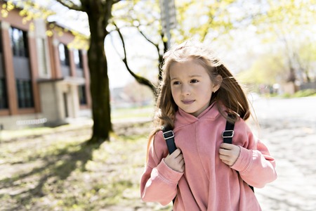 Portrait of cute girl with backpack outside of schoolの写真素材