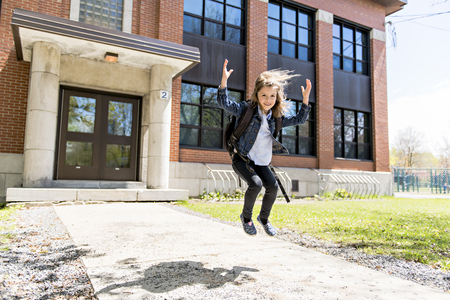 Portrait of cute girl with backpack outside of schoolの写真素材