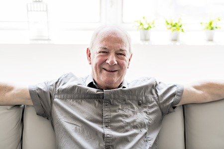 Senior man at home on the sofaの写真素材