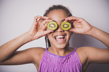 Black girl child with kiwi over the eyeの写真素材