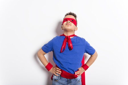 Portrait of boy in superhero costume against grey backgroundの写真素材