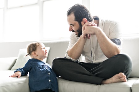 Portrait of handsome father and his cute daughter on sofaの写真素材