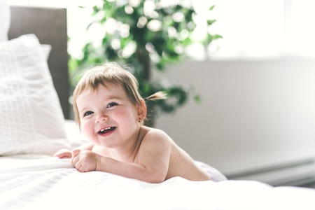 one years girl baby on the side of the bed