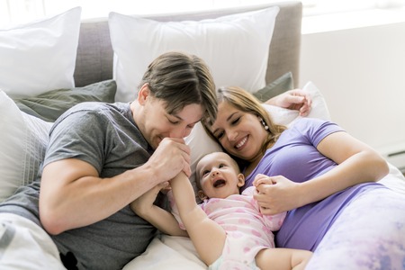 Portrait of beautiful young parents and cute baby on bed