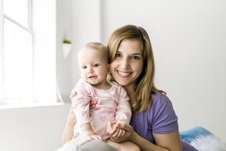 happy loving family. mother playing with her baby on the sofaの写真素材