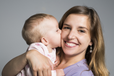 Young mother holding her little baby on studio dark grayの写真素材