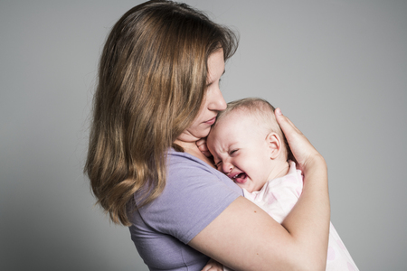 Mother trying to calm her crying babyの写真素材