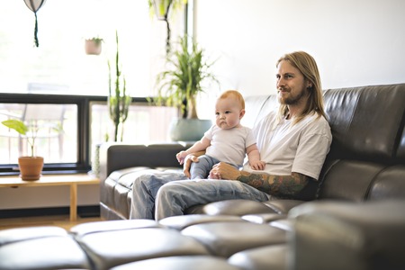 father playing with baby daughter on sofa at homeの写真素材