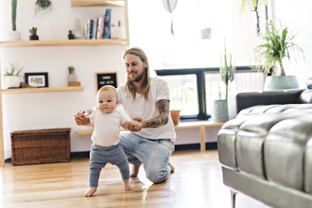 Father help Baby Daughter Take First Steps At Home